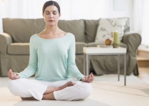 USA, New Jersey, Jersey City, Woman meditating in living room